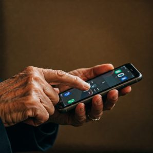 immagine secondaria magazine Mano di un anziano che sfiora uno smartphone semplificato